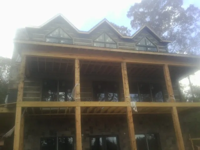 Dormers and porch framing on a large log home under construction — Roof Coating work by our crew in Dyersville