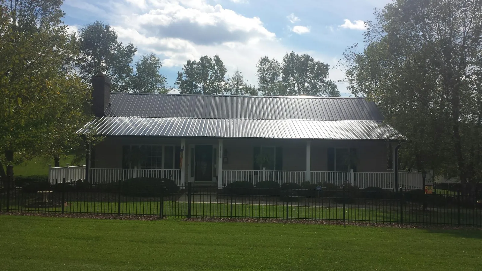 Gray metal roof on a brick ranch with a full width front porch — Gutter Guard Installation work by our crew in Dyersville