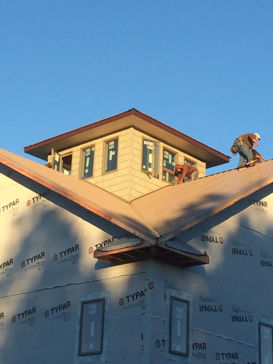 Roofers working around a rooftop cupola on a new metal roof at sunset — Roof Waterproofing in Dyersville by Roofing Brothers